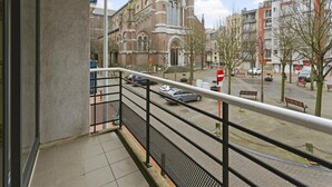 Un balcon offrant une vue sur une église historique et des immeubles modernes.