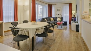 Un salon moderne avec une table de salle à manger ronde, des chaises noires, un canapé et une table basse.