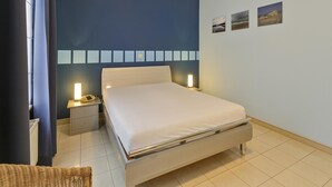 Une chambre à coucher avec un lit, des tables de chevet et des lampes fixées au mur.