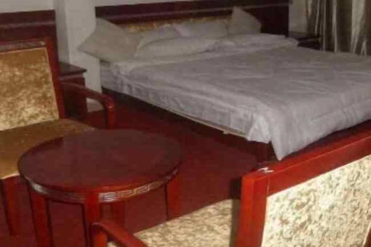 A hotel room with a single bed, a wooden nightstand, a round table, and a chair.