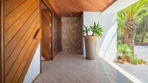 Ein Korridor mit Holzvertäfelung, einer Steinwand und einem großen Pflanzgefäß mit Pflanzen.