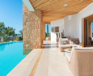 Relax by the pool with a clear view, surrounded by wicker sofas and a potted plant.
