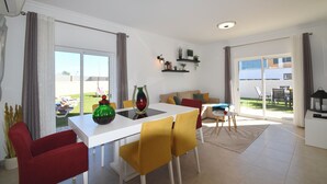 A modern living room with a white dining table, yellow chairs, a red sofa, and a large sliding glass door leading to a balcony. - Villa Barros, with private swimming pool, in a quiet and peaceful area. (Algoz)
