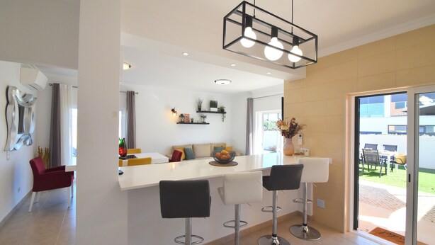 A modern kitchen with a white countertop, three bar stools, and a hanging light fixture. - Villa Barros, with private swimming pool, in a quiet and peaceful area. (Algoz)