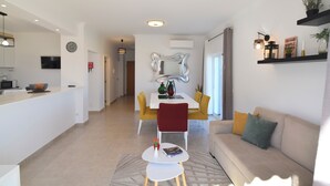 A modern living room with a sofa, a dining table with chairs, and a kitchen area with a microwave. - Villa Barros, with private swimming pool, in a quiet and peaceful area. (Algoz)