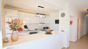 A modern kitchen with white cabinetry, a central island, and a vase of flowers. - Villa Barros, with private swimming pool, in a quiet and peaceful area. (Algoz)