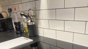A kitchen with a black induction cooktop, a white countertop, and a backsplash of white tiles.