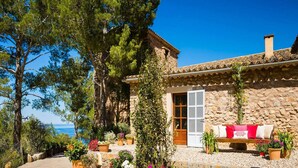 A stone house with a tiled roof, a wooden door, and a bench with cushions outside. - Traditional Villa With Private Pool (Banyalbufar)