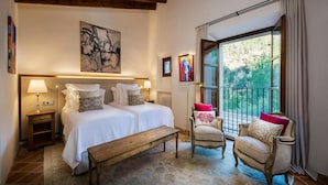 A bedroom with two beds, a bench, a chair, and a balcony with a view. - Traditional Villa With Private Pool (Banyalbufar)