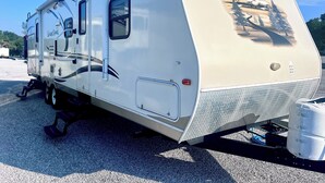 Uma motorhome com área de estar coberta, porta deslizante e uma pequena janela.