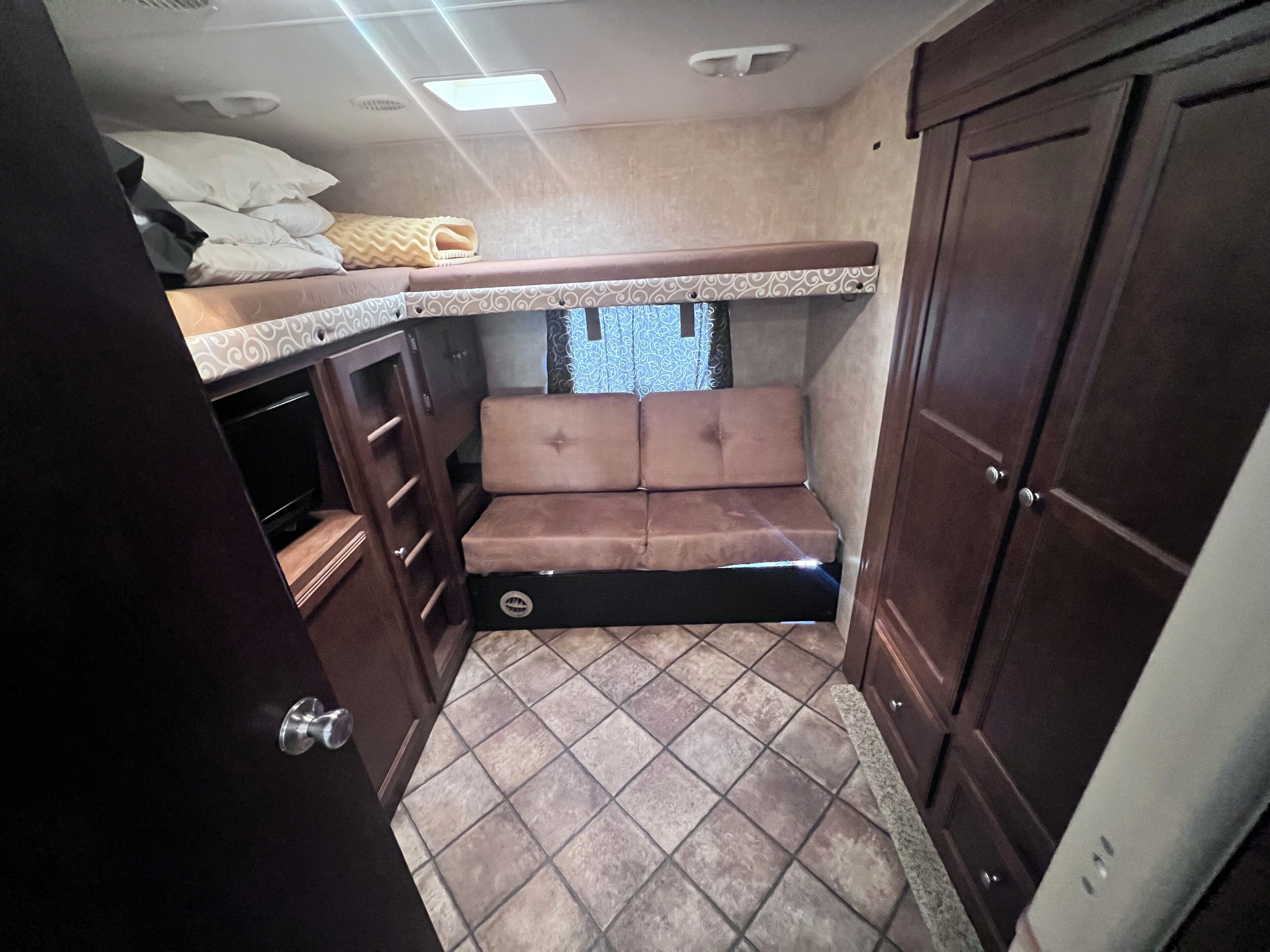 Interior compacto de una caravana con cocina americana, zona de estar y un armario de almacenamiento.