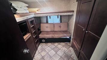 Interior compacto de una caravana con cocina americana, zona de estar y un armario de almacenamiento.