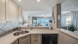A modern kitchen with a built-in dishwasher, a large window with a view, and a ceiling fan.
