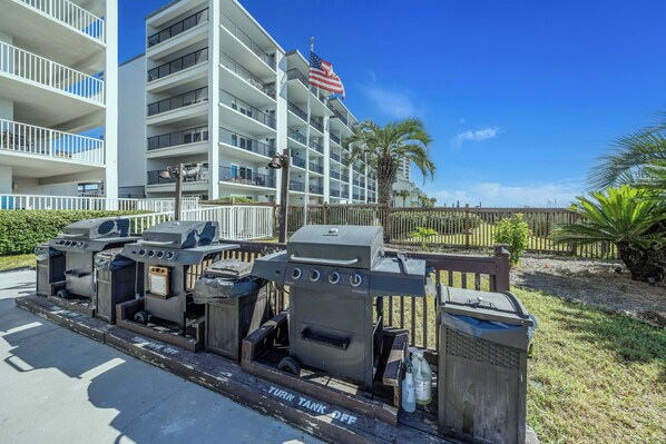 A multi-story hotel with balconies, a flag, and outdoor grills.