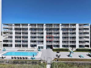 A multi-story hotel with a swimming pool, outdoor seating, and balconies. - FREE Golf & Perks! Mariner West 306- Low Floor, Pool, Tennis & BBQ Grills! (Panama City Beach)