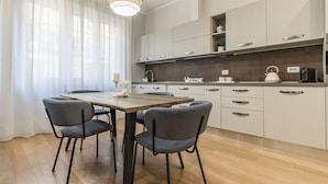A modern kitchen with a wooden table and four chairs, light-colored cabinets, and a 'Welcome' sign on the wall. - HouSmart Massarenti 61 (Bologna)