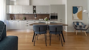 A modern kitchen with grey cabinets, a wooden dining table, and two chairs. - HouSmart Massarenti 61 (Bologna)