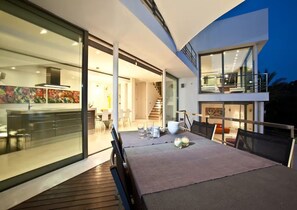 A modern house with a dining area, kitchen, and a staircase leading to an upper level.