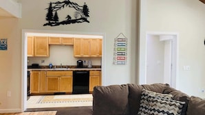 A living room with a brown sofa, a rug, and a wall decoration of a mountain scene. - Charming 2-bedroom house with AC, WiFi in tranquil Conway (Conway)