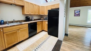A modern kitchen with wooden cabinets, a black refrigerator, and a skylight. - Charming 2-bedroom house with AC, WiFi in tranquil Conway (Conway)