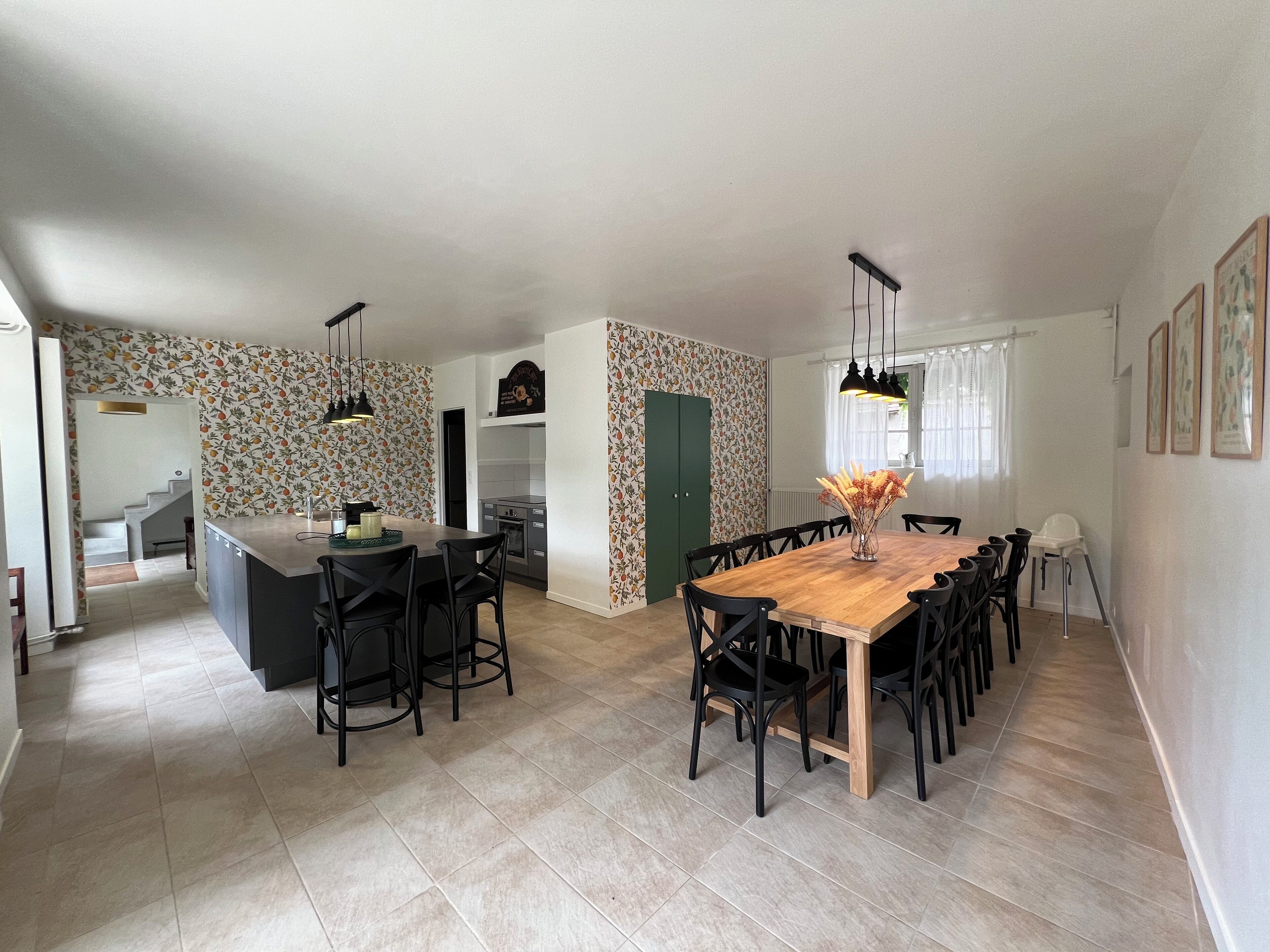 Una cocina amplia con una isla central, un comedor con una gran mesa de madera, y una isla de cocina con taburetes de bar.