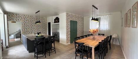 Una cocina amplia con una isla central, un comedor con una gran mesa de madera, y una isla de cocina con taburetes de bar.