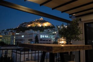 Uma varanda com vista para um edifício no topo da colina ao entardecer.