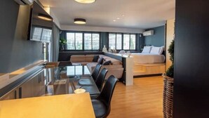 A modern living room with a glass dining table, sofas, and a built-in kitchen area. - Athens Skyline Loft

 (Athina)