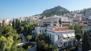 A cityscape with a prominent hill in the background, surrounded by residential buildings and lush greenery. - Athens Skyline Loft

 (Athina)