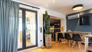 A modern kitchen with a dining area, a large window, and a flat-screen TV mounted on the wall. - Athens Skyline Loft

 (Athina)