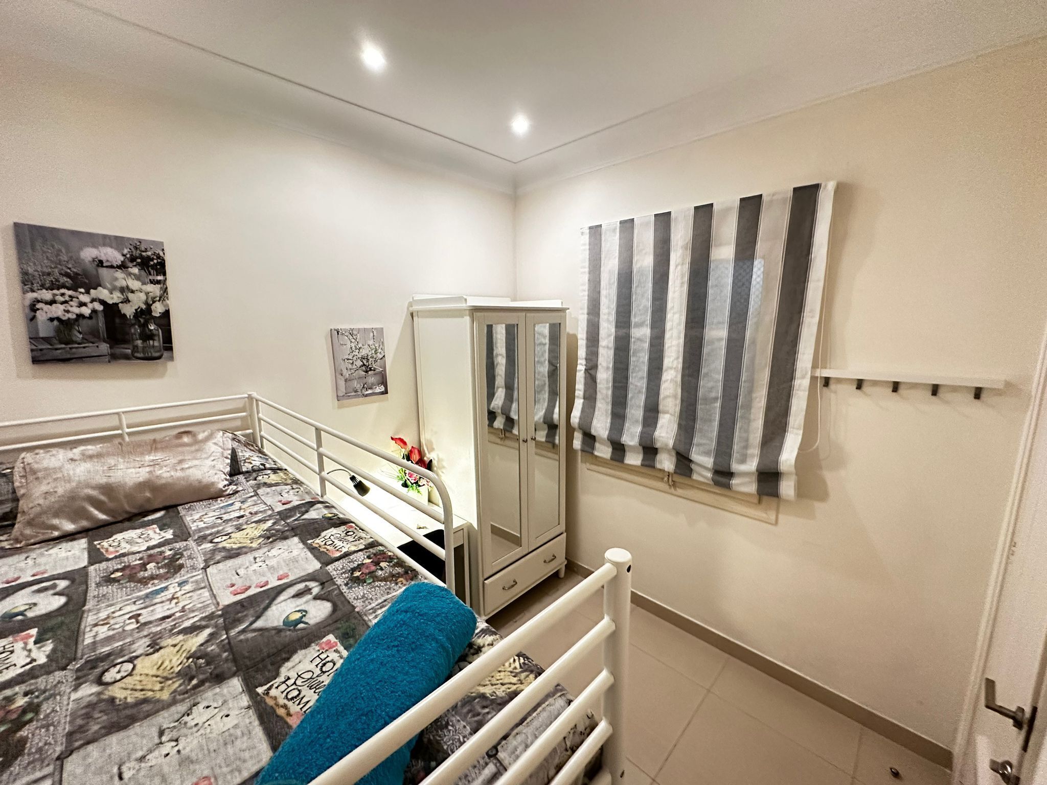 A bedroom with a bed, a wardrobe, and a window with striped curtains.