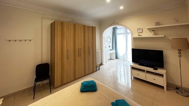 Een ruime woonkamer met een grote kledingkast, een flatscreen-tv en een bank.