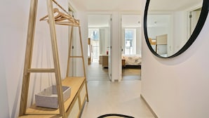 A hallway with a wooden wardrobe, a mirror, and a view into a bedroom. - Apartment in Blankenberge Near Beach (Blankenberge)