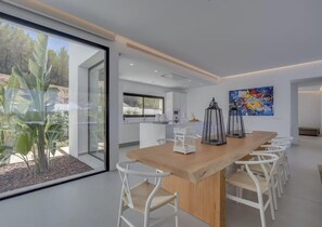 A modern kitchen with a large island, white cabinetry, and a view of the outdoors. - Sleek Villa With Nice Terrace (Sant Josep de sa Talaia)