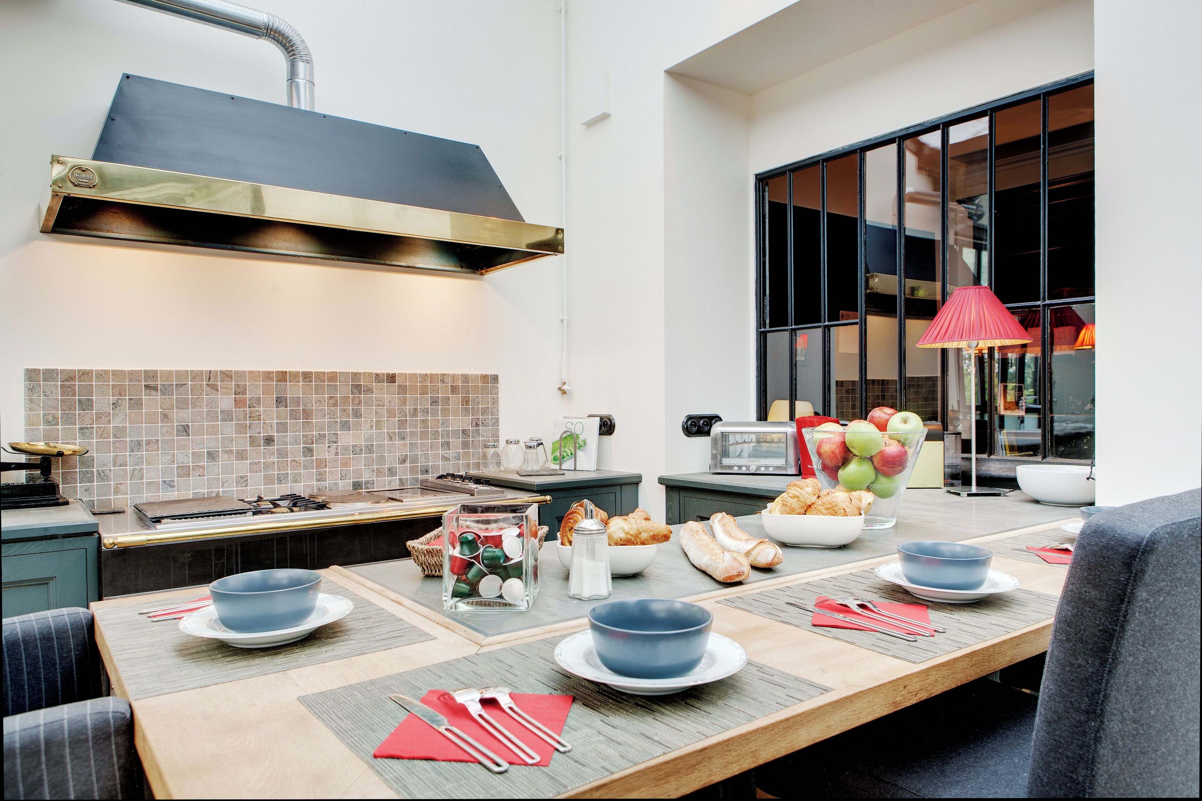 Una cocina moderna con una estufa grande, un salpicadero de azulejos y un comedor con una mesa preparada para dos.