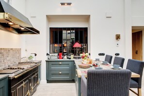 A modern kitchen with a dining area, featuring a large window, a built-in stove, and a dining table set for six. - Paris Green House Residence (Paris)