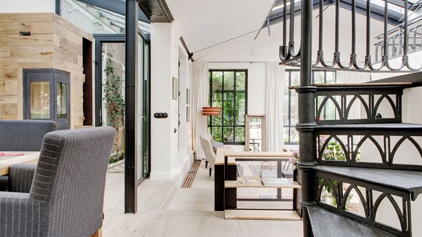 A modern interior with a dining area, a staircase, and a view of greenery outside. - Paris Green House Residence (Paris)