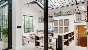 A spacious living area with a high ceiling, a staircase, and a balcony with plants. - Paris Green House Residence (Paris)