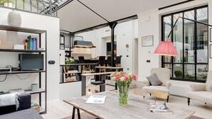 A modern living room with a wooden coffee table, a bookshelf, a sofa, and a large window with a view. - Paris Green House Residence (Paris)