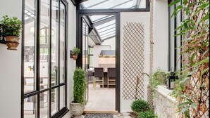 A narrow entrance with a glass door leading to a patio area with a table and chairs. - Paris Green House Residence (Paris)