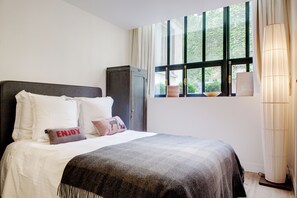 A neatly made bed with white and gray bedding, a dark headboard, and decorative pillows including one with "ENJOY" written on it. - Paris Green House Residence (Paris)