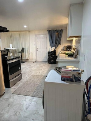 Cozinha compacta com fogão, forno e uma bancada pequena com pia.