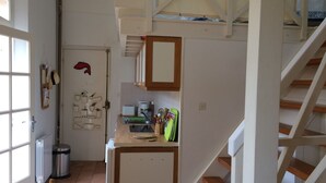 Une cuisine de taille réduite, équipée d’un évier, d’un plan de travail et d’un escalier en bois.
