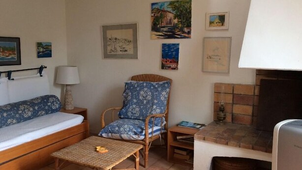 Un salon avec un canapé, un fauteuil à motifs, une petite table et une cheminée.