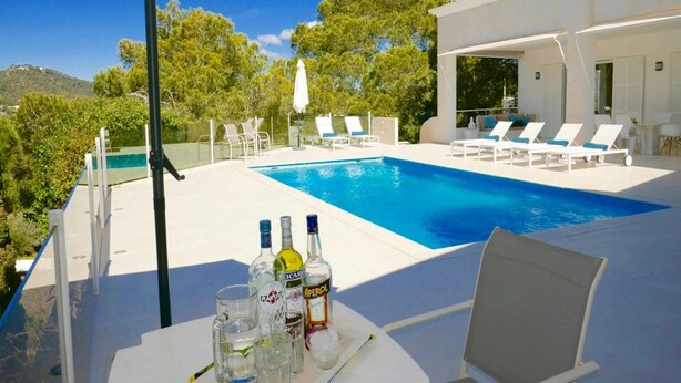A poolside area with a clear view of the pool, lounge chairs, and a table with bottles and glasses. - Villa With Golf-course Views (Santa Eulalia del Rio)