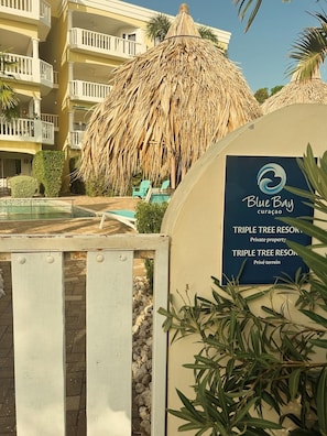 A resort entrance with a sign for Blue Bay Curacao, a private property named Triple Tree Resort. - Blue Bay 'the Hill", splendid view, close to beach, AC, swimming pool, gated (Sint Michiel)