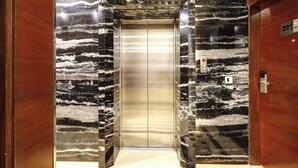 An elevator with marble walls and a wooden door.