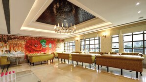 A spacious lobby with a large seating area, a decorative mural, and a chandelier.