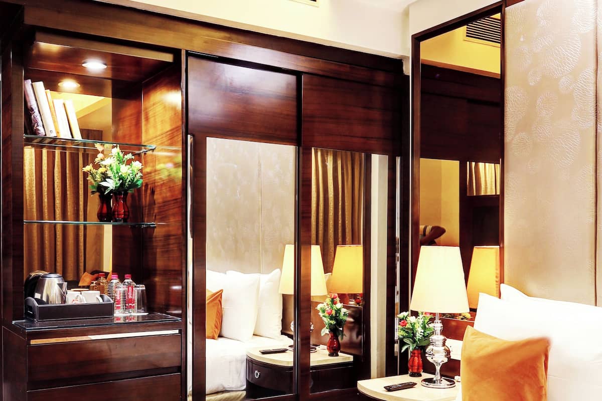 A hotel room with a bed, bedside tables, a mirror, and a wardrobe.