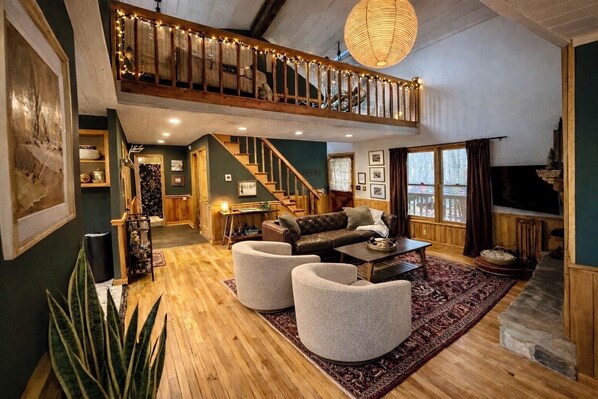 A spacious living area with a staircase leading to an upper level, a fireplace, and a television.